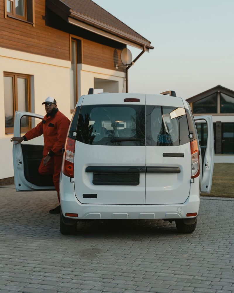 Service technician stepping out of a white work van parked in a home's driveway
